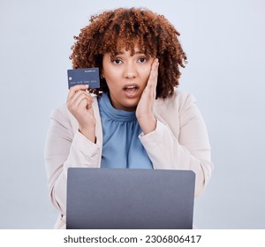 Shocked woman holding a credit card while looking at her laptop screen